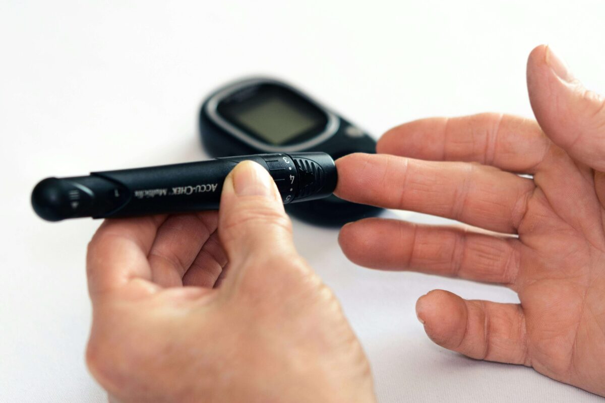 A person is checking his Diabetes by a Glucometer placed at his fingers.