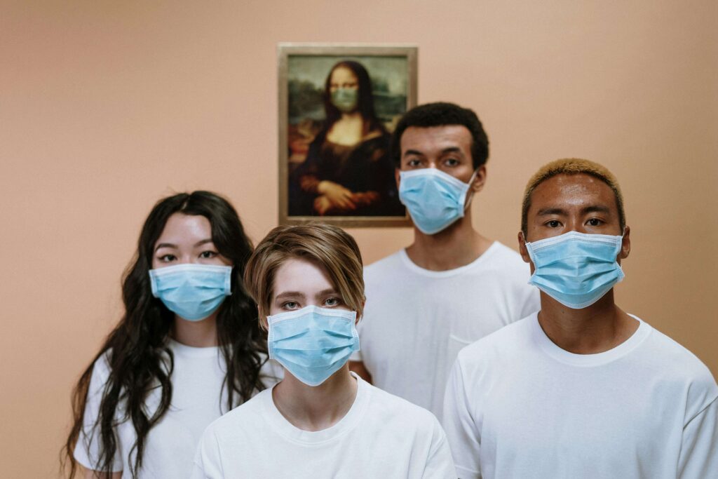 Two males and two females wearing face mask for Long COVID standing in front of picture of Mona Lisa hanged on a wall.