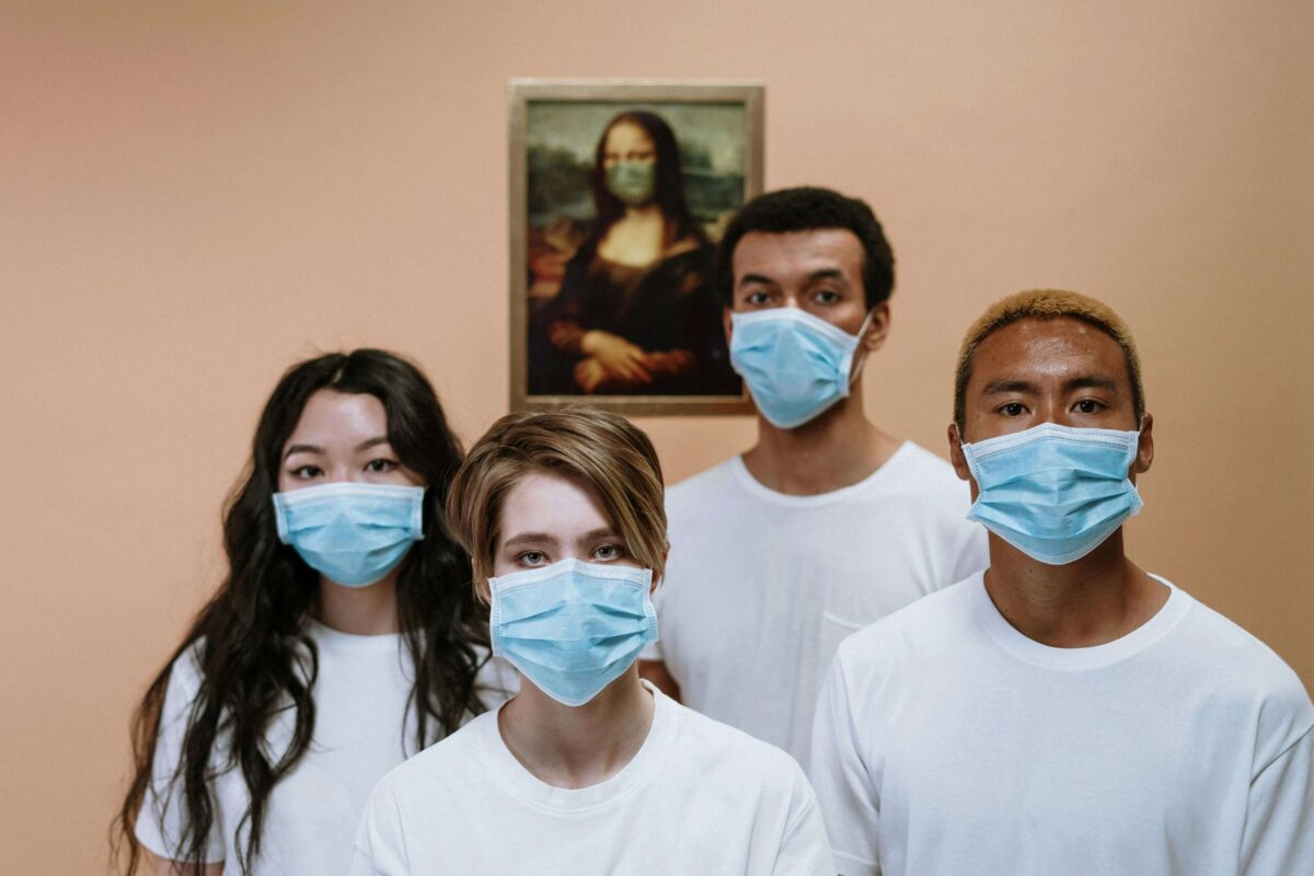 Two males and two females wearing face mask for Long COVID standing in front of picture of Mona Lisa hanged on a wall.